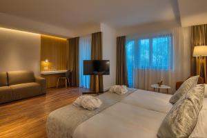 una camera d'albergo con un grande letto e una TV di Cardoner Hotel és Konferenciaközpont a Dobogókő