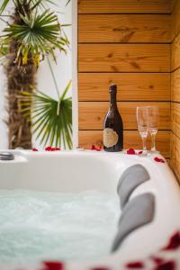 eine Badewanne mit einer Flasche und zwei Gläsern in der Unterkunft Casa Gauda — Jacuzzi, relaxation & serenity in Falaise