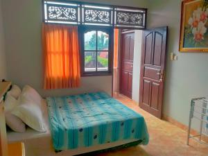 a bedroom with a bed and a window at Umah GEOKS in Darmasaba