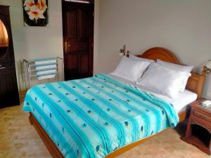 a bedroom with a large bed with a blue comforter at Umah GEOKS in Darmasaba