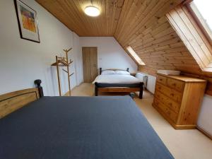 Ski/Bike Villa Sapporo ⃰ ⃰ ⃰ في Kraslice: غرفة نوم علوية بسرير وسقف خشبي