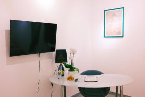 a white table with a chair and a tv on a wall at Termini Rita House in Rome