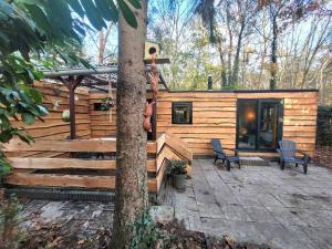 eine Blockhütte mit 2 Stühlen und einer Terrasse in der Unterkunft Verblijf midden in de natuur in de Jagershut! in Hattemerbroek