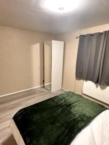 Apartment in Greenwich في لندن: غرفة نوم مع بطانية خضراء على سرير
