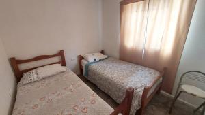 two beds in a small room with a window at Cabañas Imperio Pisco Elqui in Pisco Elqui