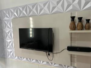 a flat screen tv hanging on a wall with vases at Ótima localização centro de Juazeiro in Juazeiro