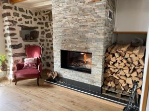 a fireplace with a chair and a pile of fire wood at La grande garde in Les Avants