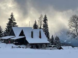 a house covered in snow in front of trees at La grande garde in Les Avants