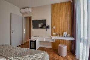 ein Schlafzimmer mit einem Bett und einem Fernseher an der Wand in der Unterkunft Cardoner Hotel és Konferenciaközpont in Dobogókő