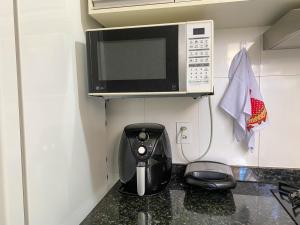 a kitchen with a coffee maker under a microwave at A 500m da PRAIA de Taperapuan, 2 quartos, até 6 pessoas, WiFi 300mbs, Churrasqueira, Chuveirão, Smart TV, Estacionamento Gratuito in Porto Seguro