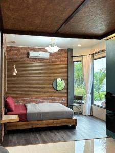 a bedroom with a bed and a brick wall at Cafe'@luv22 in Phuket Town