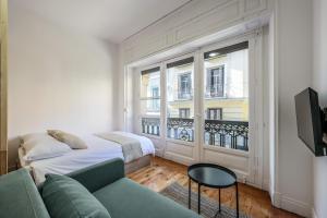 - un salon avec un canapé et une grande fenêtre dans l'établissement Victoria Apartments, à Madrid