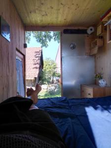 eine Person, die in einem Zimmer mit Fenster auf einem Bett liegt in der Unterkunft Schäferwagen Hotzenplotz 