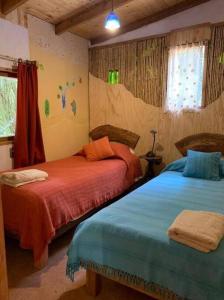 a bedroom with two beds with orange and blue at Cabaña entre Boldos in Villarrica