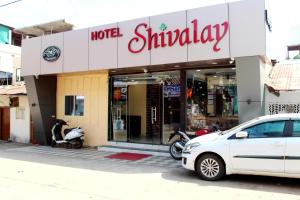 una macchina bianca parcheggiata di fronte a un negozio di HOTEL SHIVALAY a Pachmarhī