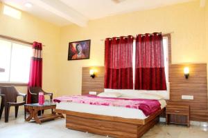 a bedroom with a bed with red curtains at HOTEL SHIVALAY in Pachmarhī