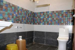 uma casa de banho com WC e azulejos na parede em HOTEL SHIVALAY em Pachmarhī