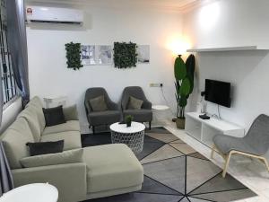 sala de estar con sofá, sillas y TV en Dahlia Homestay (Wi-Fi & Netflix), en Miri