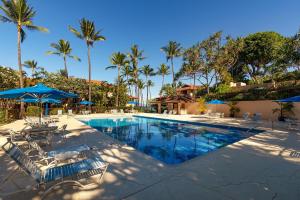 a swimming pool with chairs and umbrellas and palm trees at Makena Surf G-201 - End Unit, Panoramic Views, AC! in Wailea