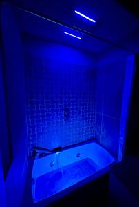 a dark bathroom with a tub with blue lighting at OliVia Rooms Sauna & Gym in Forlì