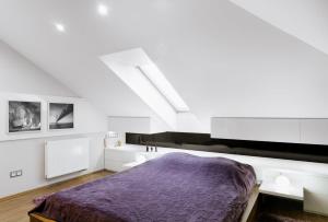 sypialnia z fioletowym łóżkiem w białym pokoju w obiekcie Wrzosowy Apartament w mieście Sosnowiec