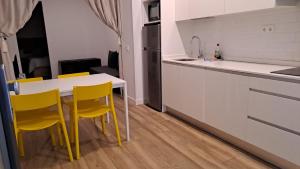 a kitchen with a table and yellow chairs at nuevo refugio en los bajos de Moncloa! in Madrid