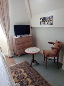 sala de estar con TV, mesa y silla en Appartements Villa Odette, en Bagnoles de l'Orne