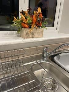 a kitchen sink with a vase of flowers on a window ledge at Immaculate house in Doncaster 2 in Doncaster
