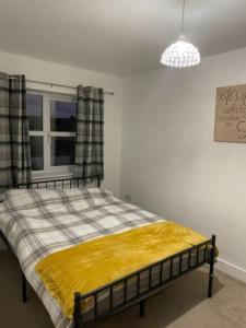 a bedroom with a bed with a yellow blanket on it at Immaculate house in Doncaster 2 in Doncaster