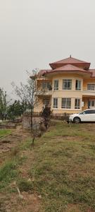 een witte auto geparkeerd voor een groot huis bij Indrayanifarms in Sundarijal