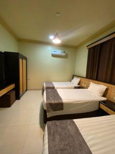 a bedroom with two beds and a flat screen tv at ديار البساتين المنسك للشقق الفندقية - Diyar Al Basateen Hotel Apartments in Abha