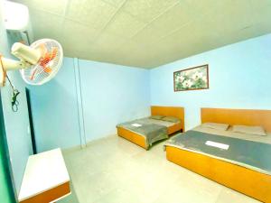 Cette chambre comprend deux lits et un ventilateur. dans l'établissement Nhà nghỉ Đoàn Gia, à Dồng Xoài