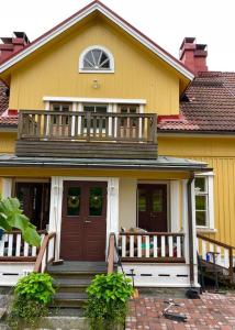 a yellow house with a porch and a balcony at Satavuotias helmi Mäntässä in Mänttä