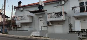 a white house with two balconies on a street at Skordas Comfy Rent Rooms in Thessaloniki