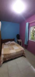 una camera da letto con un letto con pareti viola e una finestra di Casa a 300 metros da Praia da Pinheira ,3 km da Guarda do Embaú Sc a Palhoça