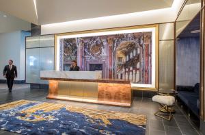 a woman standing in a lobby with a painting on the wall at The Laura Hotel, Houston Downtown, Autograph Collection in Houston