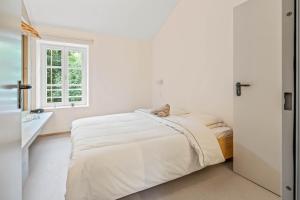 a white bedroom with a bed and a window at Maison Lasauvage in Differdange