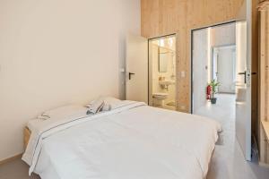 a bedroom with a large white bed and a bathroom at Maison Lasauvage in Differdange