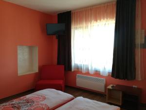 1 dormitorio con cama, silla roja y ventana en Къща за гости Вила Смокиня град Хисаря en Hisarya