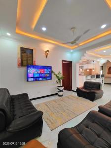 a living room with couches and a flat screen tv at Ayaa Luxury Apartment 3rd Floor Zanzibar in Ngambo