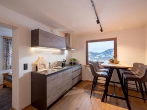 een keuken met een wastafel, een tafel en een raam bij Appartement Penningdörfl in Hopfgarten im Brixental