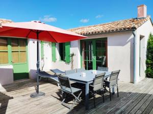 une table et des chaises avec un parasol rouge sur une terrasse dans l'établissement Villa Green Oaks, à Rivedoux-Plage