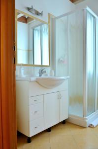 a white bathroom with a sink and a shower at White Garden - Apartment with access to the Lake in Lierna