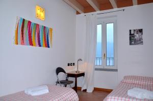 a bedroom with two beds and a desk and a window at White Garden - Apartment with access to the Lake in Lierna