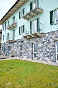 a building with balconies and a grass yard at White Garden - Apartment with access to the Lake in Lierna