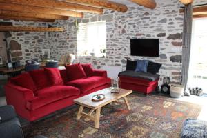 una sala de estar con muebles de color rojo y una pared de piedra. en Maison La pierre du lezard, 