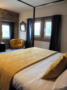 um quarto com uma cama, uma cadeira e janelas em Quinta de Moçamedes - Turismo de Habitação em Vouzela