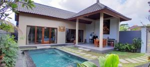 a house with a swimming pool in front of it at Umah Landuh in Ubud