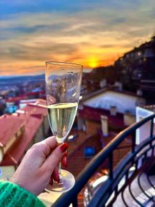 osoba trzymająca kieliszek wina na balkonie w obiekcie TOP SKY VIEW - Studio Panorama w mieście Wielkie Tyrnowo