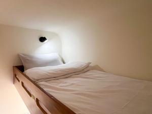 頭城的住宿－水旅居露營車，一张铺有白色床单的床和墙上的灯